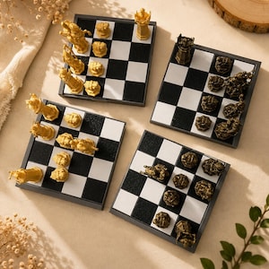 May include: Four square chess boards with black and white checkered patterns. Two boards feature gold-colored chess pieces, while the other two boards feature dark bronze-colored chess pieces. The pieces are sculpted with intricate, detailed designs.