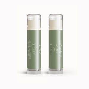 May include: Two lip balm tubes with olive green labels. The labels read "LESLIE and ANDY" and "THANK YOU FOR CELEBRATING WITH US!". The other tube reads "LESLIE and ANDY NOVEMBER 15, 20XX". The tubes have clear caps.