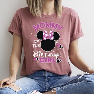 May include: A mauve t-shirt with the text "Mommy of the Birthday Girl" and a Minnie Mouse design. The design includes stars and Minnie Mouse icons. Ideal for a birthday celebration. The t-shirt is a relaxed fit.