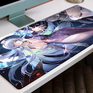 May include: A rectangular desk mat featuring a fantasy illustration of a woman with long, flowing silver hair and a purple and white outfit. The artwork has a celestial theme with blue and white accents.