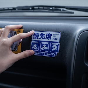May include: A blue and white sticker with the text "Priority Seat" in Japanese and English. The sticker also includes three icons: a pair of shoes, a pair of gloves, and a helmet. The text below the icons reads "This seat is for racers only."