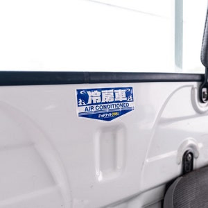 May include: A blue and white sticker with the text "冷房車 AIR CONDITIONED" and the Japanese text "ミッドナイトクーラー" on a white surface.