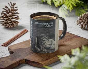 May include: A black coffee mug with a white design featuring a man and the text "A Confederacy of Dunces".
