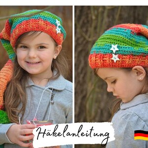May include: A child wearing a colorful crocheted hat with a long tail. The hat has a green, orange, and blue striped pattern with white star-shaped buttons. The child is wearing a gray sweater and has a German flag on their sleeve. The text "Häkelanleitung" is visible in the image.