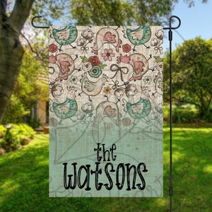 以下が含まれることがあります： 農家のテーマの緑と茶色の庭の旗。鶏、花、そして「the Watsons」という文字のパターンが描かれています。