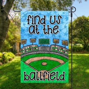 May include: A colorful garden flag with a blue sky background and white stars. The flag says "Find us at the ballfield".
