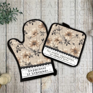 May include: A set of two beige oven mitts with a floral pattern and black trim. The larger mitt has the text "happiness is homemade" and the smaller mitt has the text "the secret ingredient is always love".