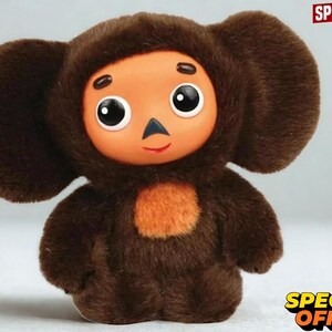May include: A plush toy featuring a brown furry body with large rounded ears and a smooth orange face. The character has large black and white eyes, a small triangular nose, and a light orange patch on its chest. The text SPECIAL OFFER is visible.