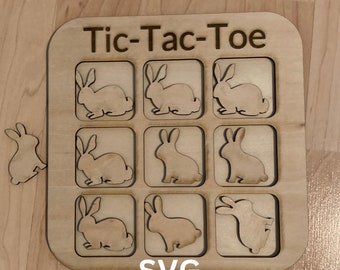 May include: A wooden Tic-Tac-Toe game with bunny-shaped pieces. The game board is laser cut and has the text "Tic-Tac-Toe" and "SVG" printed on it. The text "DIY Tic-Tac-Toe Laser Cut File" and a download button are also visible.