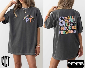 May include: Two gray t-shirts with different designs. The first shirt has the text "Physical Therapy PT" in a rainbow arc. The second shirt has the text "Small Steps Still Move Us Forward" with a graphic of crutches and a cane.