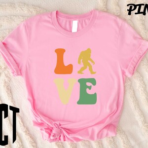 a pink shirt that says love with a bigfoot on it