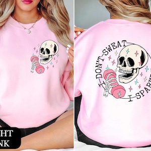 a woman wearing a pink sweatshirt with a skull on it