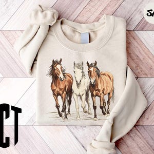 a sweater with three horses on it on a wooden floor