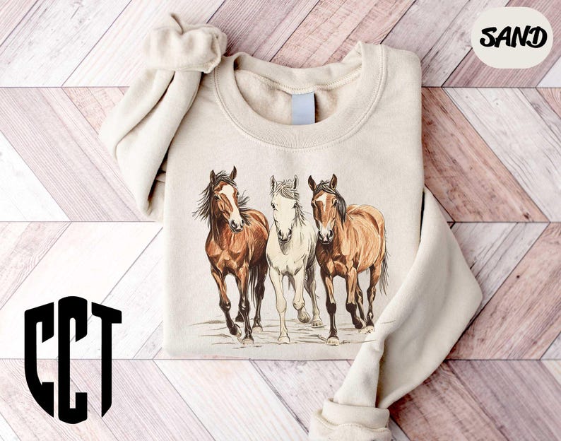 a sweater with three horses on it on a wooden floor