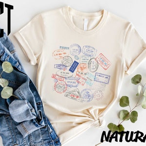 a t - shirt with stamps on it next to a pair of jeans