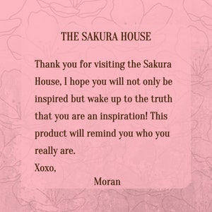 May include: A pink and white floral background with a white rectangle containing a message in brown text. The text reads "THE SAKURA HOUSE" and "Thank you for visiting the Sakura House, I hope you will not only be inspired but wake up to the truth that you are an inspiration! This product will remind you who you really are. Xoxo, Moran".