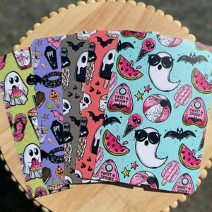 May include: Five rectangular sheets featuring colorful patterns of ghosts, bats, watermelons, and ice cream. The designs include pink, blue, green, and purple backgrounds with the text Sweet & Spooky on small planchette-shaped icons.