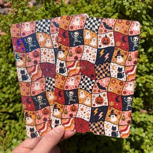 May include: Two rectangular cards featuring a repeating grid pattern of wavy squares. The design includes Halloween-themed illustrations such as ghosts, skeletons, pumpkins, black cats, bats, spiderwebs, moons, stars, and checkered motifs in orange, pink, black, and white.