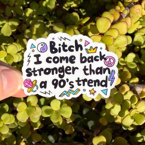 May include: A white die-cut sticker featuring the black text "Bitch I come back stronger than a 90's trend" surrounded by colorful illustrations including a yin-yang symbol, a crown, a peace sign, a diamond, a lightning bolt, and geometric shapes.