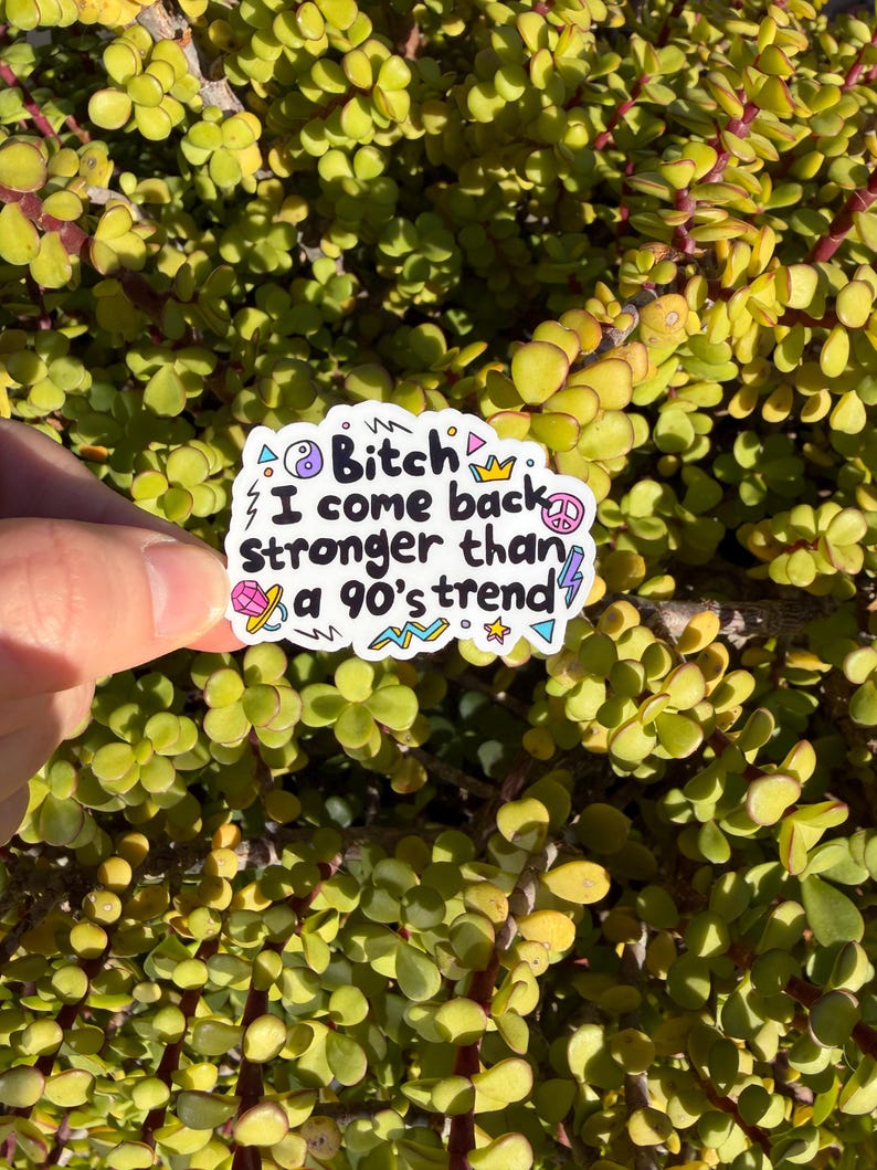 May include: A white die-cut sticker featuring the black text "Bitch I come back stronger than a 90's trend" surrounded by colorful illustrations including a yin-yang symbol, a crown, a peace sign, a diamond, a lightning bolt, and geometric shapes.