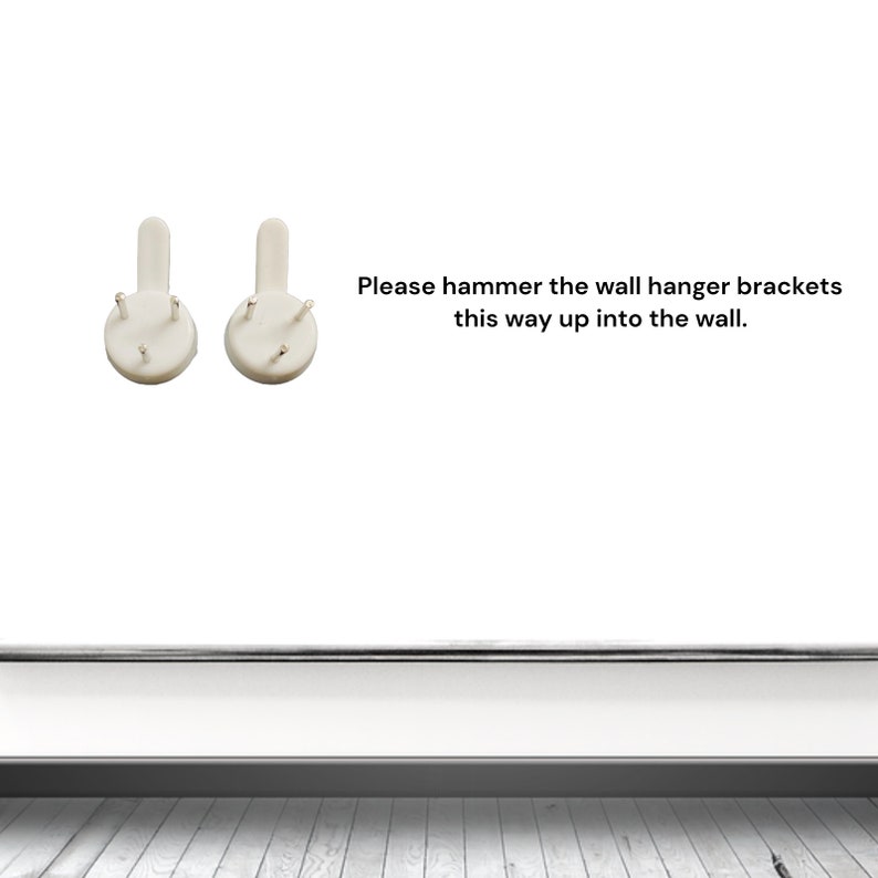 May include: Two white wall hanger brackets with four small pins each. The brackets are designed to be hammered into a wall. Text on the image reads: "Please hammer the wall hanger brackets this way up into the wall."