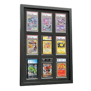 Op de afbeelding: Een zwart omkaderde displaycase met negen beoordeelde Pok&eacute;mon-ruilkaarten. De kaarten bevatten verschillende personages en zijn ingekapseld in doorzichtige beschermhouders. Het frame is rechthoekig en heeft een donkere afwerking.