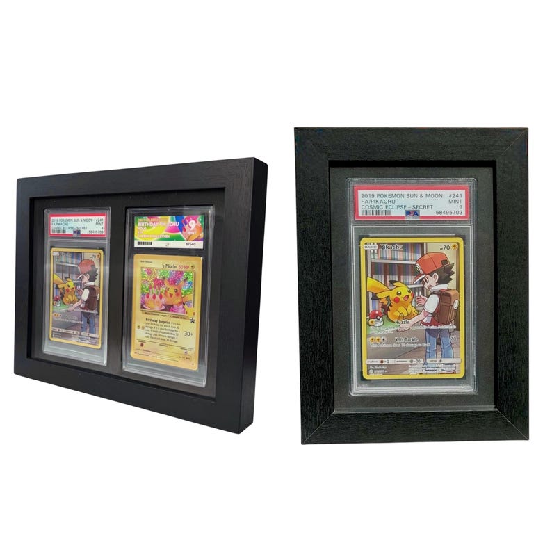Op de afbeelding: Twee zwart omlijste displays met Pok&eacute;mon-verzamelkaarten. E&eacute;n frame bevat drie kaarten, de andere &eacute;&eacute;n kaart. De kaarten bevatten kleurrijke illustraties van Pikachu en andere personages. De display met &eacute;&eacute;n kaart heeft de tekst "2018 POKEMON SUN & MOON".