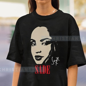 Może przedstawiać: Czarny T-shirt z czarno-białym obrazkiem Sade, piosenkarki, z jej podpisem i słowem "SADE" w czerwonych literach.
