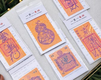 May include: A collection of small, rectangular cards with orange and white backgrounds, featuring purple and red Chinese characters and illustrations. Each card is sealed in a clear plastic sleeve. The text "ONE LEAF AND ONE CINNABAR" is printed on the top of each card.