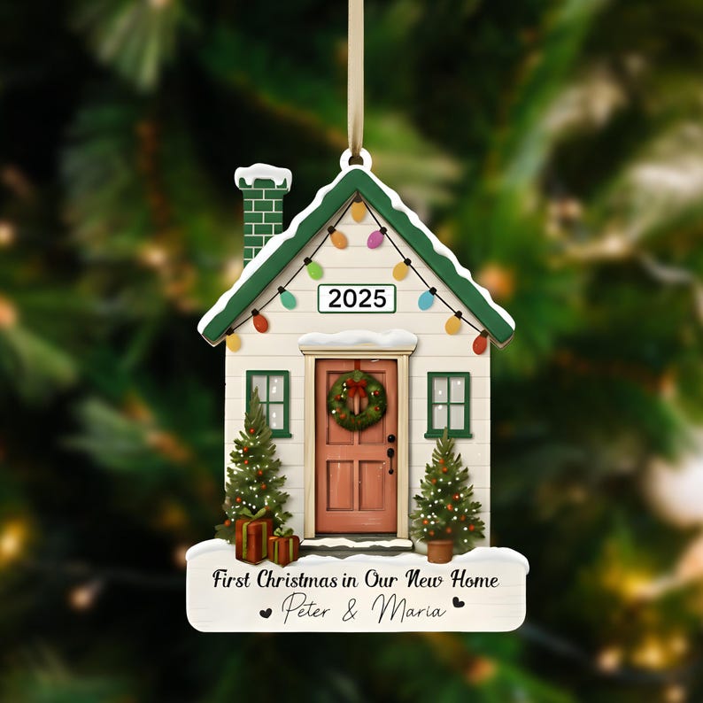 Pu&ograve; includere: Un ornamento natalizio a forma di casa con tetto verde, porta rosa e una ghirlanda. L'ornamento mostra l'anno 2025, con la scritta "First Christmas in Our New Home" e i nomi "Peter & Maria".