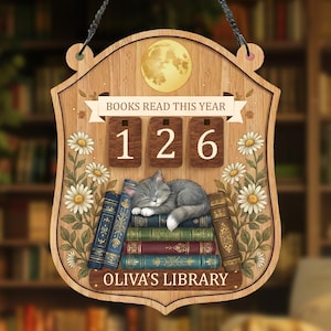 May include: Wooden sign with a cat sleeping on books, with the text "BOOKS READ THIS YEAR 126" and "OLIVA'S LIBRARY". The sign has a full moon and floral accents, perfect for a library or reading nook.