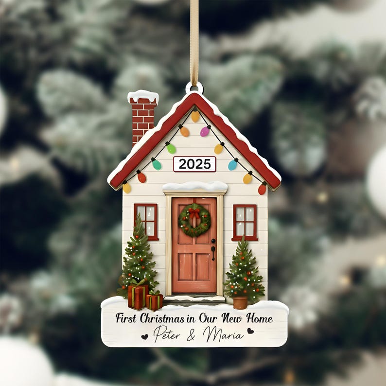 Pu&ograve; includere: Un ornamento natalizio a forma di casa con tetto rosso, camino in mattoni e luci a catena. L'ornamento presenta una porta rossa con una ghirlanda, due piccoli alberi di Natale e il testo "First Christmas in Our New Home - Peter & Maria" e l'anno 2025.