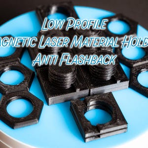 May include: Black laser material holders with a hexagonal design and circular openings, arranged on a light blue surface. The text "LOW PROFILE MAGNETIC LASER MATERIAL HOLDER ANTI FLASHBACK" is visible.