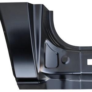 May include: A black metal automotive body panel with a curved section and several angular planes. The panel has a square opening and a circular indentation. The surface reflects light, highlighting its shape and form.