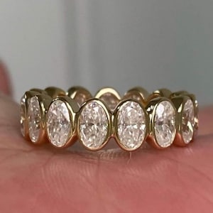 Könnte beinhalten: Ein Goldring mit einer Reihe von ovalen Diamanten, die in einer durchgehenden Linie gefasst sind.