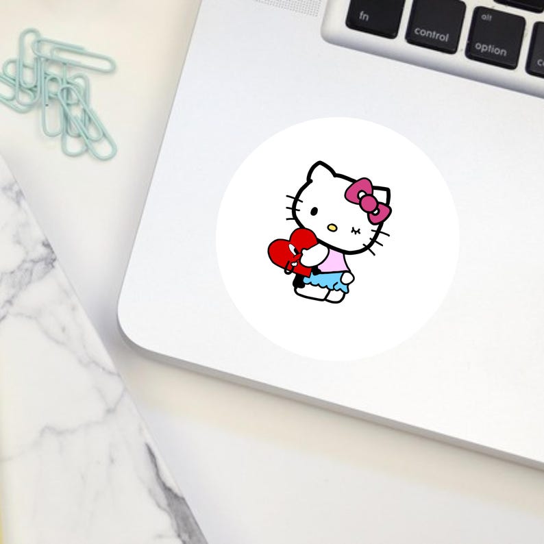 Puede incluir: Un personaje blanco de Hello Kitty con un lazo rosa sosteniendo un coraz&oacute;n rojo con una venda blanca. El personaje lleva una camisa rosa y una falda azul.