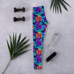 Könnte beinhalten: Leggings mit einem farbenfrohen Blumenmuster in Lila, Blau, Orange und Grün. Die Leggings werden mit schwarzen Kurzhanteln, einer Wasserflasche und einem schwarzen Trainingsband auf einer grauen Oberfläche gezeigt.