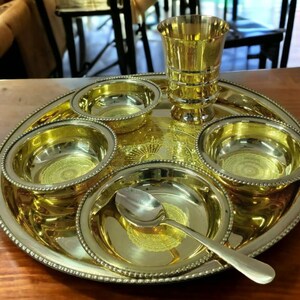 May include: A gold-toned metal serving tray with five bowls and a small cup. The tray has a beaded edge and a decorative design. The bowls and cup are also gold-toned metal.