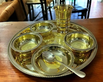 May include: A gold-toned metal serving tray with five bowls and a small cup. The tray has a beaded edge and a decorative design. The bowls and cup are also gold-toned metal.
