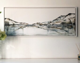 May include: A framed abstract landscape painting with a white frame. The painting features a muted color palette of grays, browns, and blues. The painting depicts a mountain range reflected in a body of water.