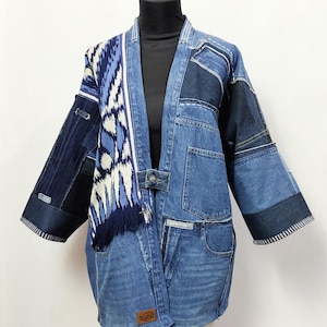 Könnte beinhalten: Eine blaue Jeansjacke mit Patchwork-Design und einem blau-weiß gemusterten Schal. Die Jacke hat ein "RUED"-Etikett unten links.