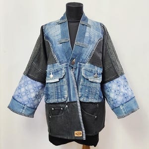 Puede incluir: Chaqueta vaquera patchwork en tonos azules y grises. La chaqueta presenta múltiples bolsillos, costuras decorativas y mangas estampadas. Tiene un diseño único con cierre de botón y una etiqueta que dice "Ruze".