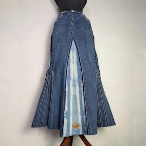 Könnte beinhalten: Langer Jeansrock mit ausgestelltem Saum und einem Mittelteil mit blau-weißem Batikmuster. Der Rock hat eine hohe Taille und einen Used-Look, mit dem Wort "Ruze" auf einem kleinen Aufnäher.