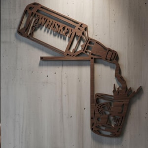 May include: Wooden wall art depicting a whiskey bottle pouring into a glass. The word "WHISKEY" is cut out of the bottle. The art is made of dark brown wood and mounted on a gray concrete wall.