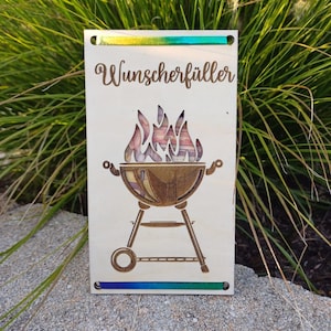 Könnte beinhalten: Ein Holzschild mit einem regenbogenfarbenen, irisierenden Rand. Das Schild hat ein Laser-Cut-Design eines Grills mit Flammen. Der Text "Wunscherschüller" ist auf dem Schild geschrieben.
