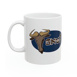 Puede incluir: Taza de cerámica blanca con un gráfico ovalado azul que presenta un ñu de dibujos animados y el texto hebreo "GNU?" en letras marrones.