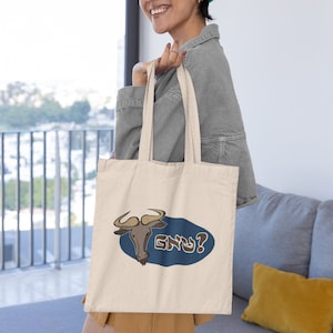 May include: A beige tote bag featuring a cartoon illustration of a brown and tan wildebeest with the text "GNU?" in blue letters on a blue oval.