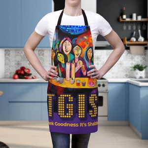 May include: A purple and yellow kitchen apron with a colorful painting of people around a table with candles. The text "Thank Goodness It's Shabbat" is printed on the bottom of the apron.