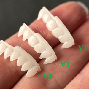 May include: Three sets of white plastic vampire teeth, labelled V1, V2, and V3. The teeth are arranged in a row, with the largest set at the top and the smallest set at the bottom.