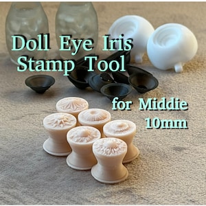 Może przedstawiać: Zestaw narzędzi do stemplowania tęczówki oka lalki i oczy lalki. Narzędzia są czarne i beżowe, z napisem "Doll Eye Iris Stamp Tool for Middie 10mm". Oczy lalki są białe.